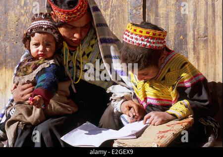 Pakistan Khyber Pakhtunkhwa Kalash Täler Bumburet Tal Mädchen ihrer Schule Aufgaben zu tun half ihrer Mutter mit kleinen Bruder auf Schoß im tiefsten Winter Ende Dezember bis Ende Februar Kalash Schulen sind geschlossen, aber Kinder haben Hausaufgaben zu Stockfoto