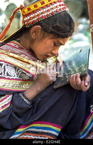 Pakistan Khyber Pakhtunkhwa Kalash Täler Bumburet Tal Schule Brun Dorf kleine Schulmädchen Kalash schreiben auf ihrem kleinen schwarzen Brett mit einem Stock in flüssiger Schlamm eingeweicht Stockfoto