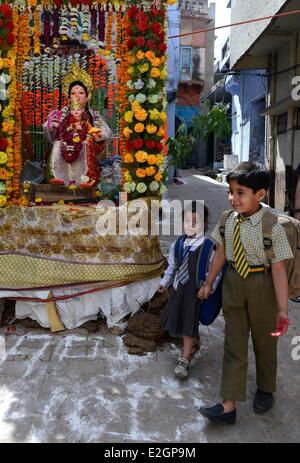 Indien Uttar Pradesh State Mathura zurückkommen ein kleiner Junge und seine kleinen Schwestern zu Hause nach der Schule vorbei an einem Tempel vor Holi Festival feiern Stockfoto