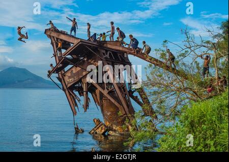 Papua-Neu-Guinea Bismarck-Archipel Gazelle Halbinsel Neubritannien Insel East New Britain Provinz Rabaul jungen springen eine rostige Wrack vor Tavurvur Vulkan Stockfoto