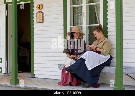 Kanada-Quebec Provinz Centre du Québec Region Drummondville Dorf Quebecois Antan altes Dorf (1810-1930) restauriert mit echten alten Gebäude zwei Frauen sprechen auf der vorderen Veranda eine stricken Stockfoto