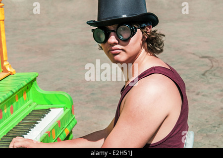 Junger Mann in einen Zylinder und Brille eine bunte Klavierspiel im Freien. Stockfoto