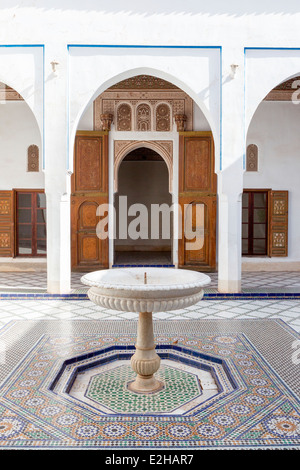 Marmor-Brunnen steht in einem Innenhof mit Zellij Fliesenarbeiten im El Bahia Palast in Marrakesch, Marokko, Nordafrika gepflastert. Stockfoto