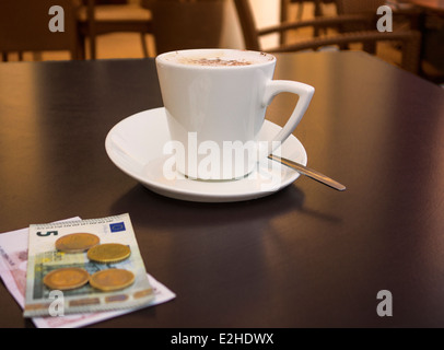 Tasse Kaffee und einige Euro auf eine Café-Tisch. Stockfoto