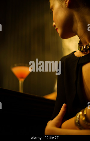 Frau sitzt alleine in Bar mit Cocktail Stockfoto