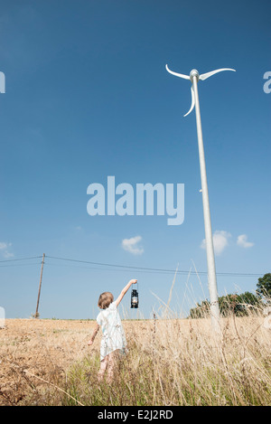 Mädchen stehen unter Windkraftanlage, Laterne, Stromleitung im Hintergrund hält Stockfoto