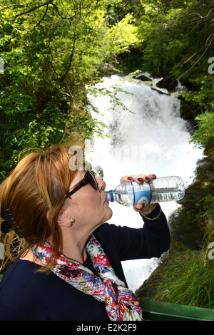 Frau trinkt Mineralwasser natürliche nächste Fiumelatte Fluss Varenna Lombardei Italien Stockfoto