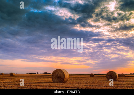 Sonnenuntergang über Feld-Hof mit Heuballen Stockfoto