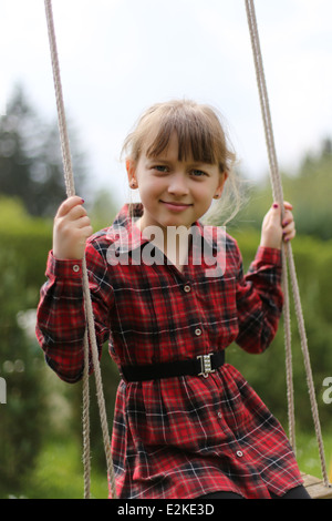 Kleines Mädchen schwingen auf einer Schaukel an Sommertag Stockfoto