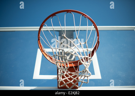 Basketballkorb mit Netz und Rückwand // ein orangener Basketballkorb mit transparentem Rückteil mit Netz gegen einen klaren blauen Himmel. Stockfoto