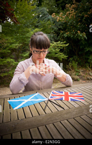 Junge Frau betrachten eine schottische und britische Flagge, die entscheiden, wie Sie in die schottische Unabhängigkeitsreferendum abstimmen Stockfoto