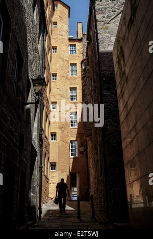 Mann zu Fuß in Richtung ein helles orange Gebäude in einer Gasse führt zu der Royal Mile, Edinburgh Stockfoto