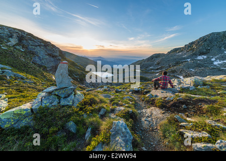 Männliche Wanderer Rast und Sonnenaufgang zu beobachten, in den italienischen Alpen. Stockfoto