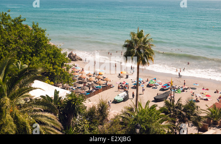 Sonnenanbeter und Strandurlauber spielen auf den bezaubernden Strand Callehonda in Nerja, Costa Del Sol, Spanien. Stockfoto