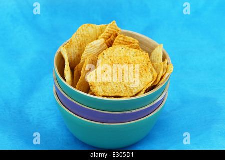 Gebackene Kartoffelchips mit frischen Kräutern auf blauem Hintergrund Stockfoto