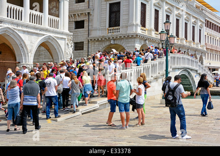 Menge von Touristen Menschen überqueren Steinbrücke an historischen Ecken Doges Palace & New Prison Gebäude durch schmalen Kanal getrennt Venedig Venetien Italien Stockfoto