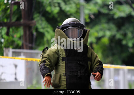 Quezon City. 22. Juni 2014. Ein Mitarbeiter aus der Bomb Squad von der Philippine National Police (PNP) tragen eine Bombe Anzug Bestellungen Zuschauer fern zu halten, nach der Prüfung eines Verdächtigen Pakets während einer Bombendrohung in der PNP Hauptsitz in Quezon City, Philippinen am 22. Juni 2014. Die Bombendrohung erwies sich als negativ sein, nachdem die Polizei im Inneren der Box Papiere gefunden. Bildnachweis: Rouelle Umali/Xinhua/Alamy Live-Nachrichten Stockfoto