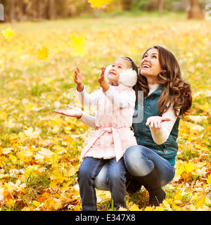 Mutter und Tochter Spaß im Herbst Park unter den fallenden Blättern. Stockfoto