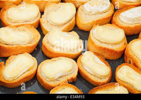 viele geröstete Brotscheiben mit geschmolzenem Ziegenkäse auf heiße Tablett Stockfoto