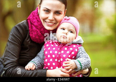 schöne junge Mutter Tochter entspannend sitzen grass Hintergrund Frühjahr grüne Wiese Grasbäume Stockfoto