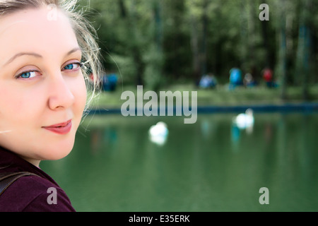 Die 35-jährige weiße blonde Frau steht in einer halben Umdrehung und lächelt im Freien. Porträt im Gesicht. Stockfoto