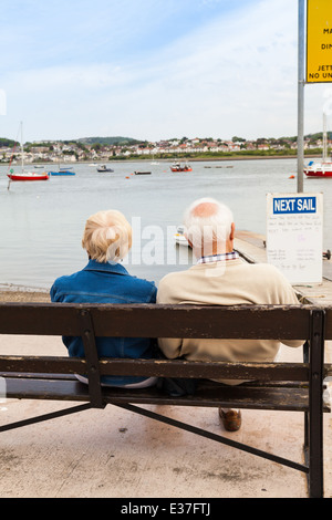 Senior paar sitzt auf hölzernen Sitzbank, das Meer bewundern Blick auf Conway Küstenort. Stockfoto