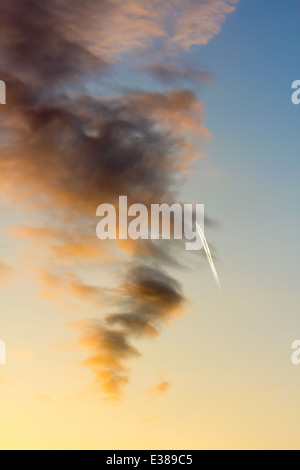 Helle weiße Rauchfahne Flugzeuge in den bewölkten Himmel bei Sonnenuntergang Stockfoto