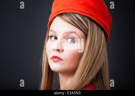 Junge Frau mit einem Vintage orange Pillbox Hut auf einem schwarzen Hintergrund. Könnte eine Zigarette Mädchen oder eine Stewardess. Stockfoto