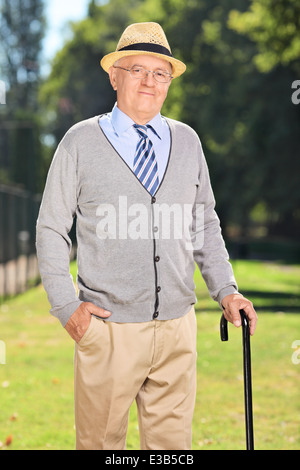 Glücklich senior Gentleman mit einem Stock posiert im park Stockfoto