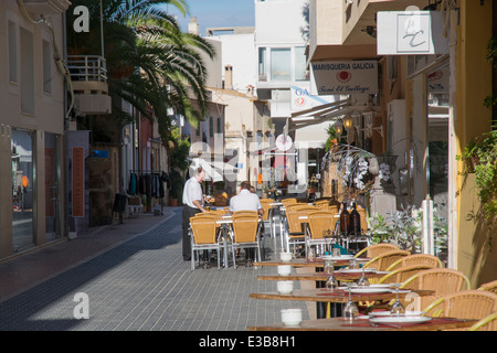 Straßenansicht in Puerto Andratx. Ein Kellner serviert ein paar Touristen im Freien im sonnigen Oktober. Stockfoto