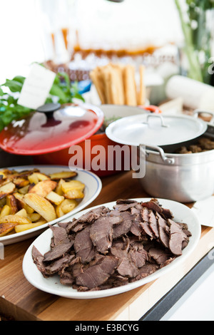 Nahaufnahme der Platten von gekochtem Fleisch und dicken Stil Pommes Frites und Frikadellen im Topf auf Tisch bereit zum Servieren bei Dinner-party Stockfoto