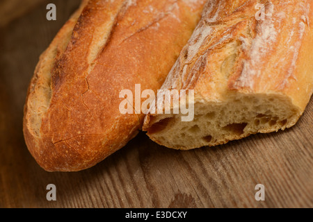 Französische knuspriges Brot, isoliert auf einem Holzbrett-Hintergrund Stockfoto