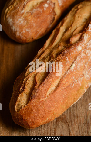 Französische knuspriges Brot, isoliert auf einem Holzbrett-Hintergrund Stockfoto