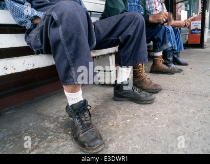 Pensionierte Landwirte in ihren blau-Jean Overall und Arbeitsstiefel entspannen und vertreiben uns die Zeit des Tages auf einer Bank vor einem Café in Lynchburg, Tennessee, USA. Stockfoto