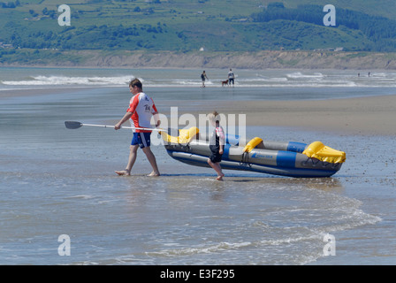 Vater holt Sohn in ein aufblasbares Kanu Stockfoto