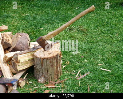 Ein Holzfäller Axt in einen Hackstock mit Spaltebrennholz um ihn herum. Stockfoto
