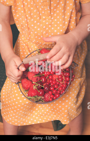 Kleines Mädchen hält Metallkorb mit Sommerfrüchten Stockfoto