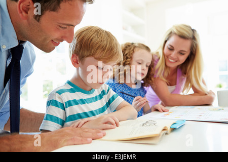 Eltern, die Hilfe für Kinder bei den Hausaufgaben In der Küche Stockfoto