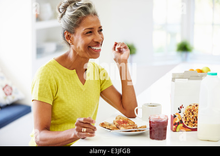 Reife Frau frühstücken und Zeitung lesen Stockfoto