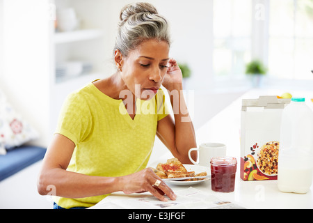 Reife Frau frühstücken und Zeitung lesen Stockfoto