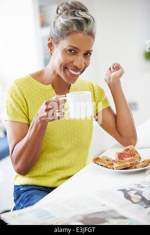 Reife Frau frühstücken und Zeitung lesen Stockfoto
