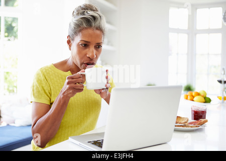 Afroamerikanische Frau mit Laptop In der Küche zu Hause Stockfoto
