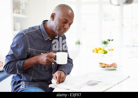 Afrikanische amerikanische Mann frühstücken und Zeitung lesen Stockfoto