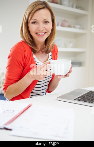 Frau arbeitet von zu Hause mit Laptop In Küche Stockfoto