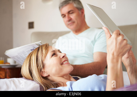 Paar erholsame im Bett mit Zeitung und Digital-Tablette Stockfoto
