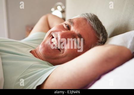 Im mittleren Alter Mann aufwachen im Bett Stockfoto