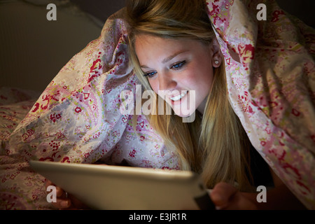 Teenager-Mädchen mit Digital-Tablette im Bett in der Nacht Stockfoto