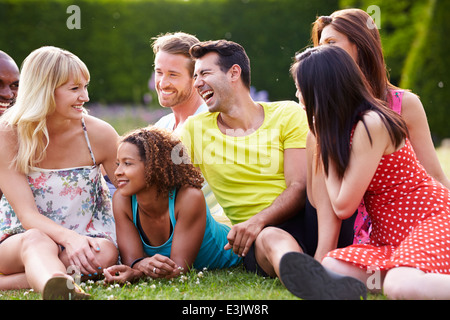 Gruppe von Freunden Zusammensitzen auf Rasen Stockfoto