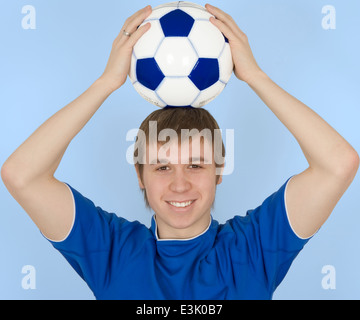 Junger Mann hält Fußball auf Kopf, Lächeln, Porträt Stockfoto
