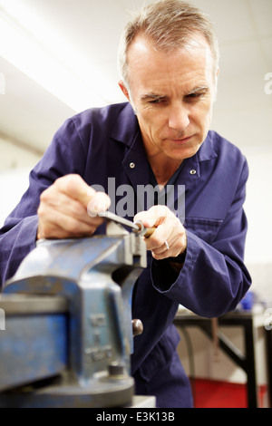 Ingenieur mit Metallfeile in Fabrikhalle Stockfoto